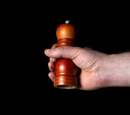Person is hand holding Pepper Grinder close-up on black backgroundの写真素材