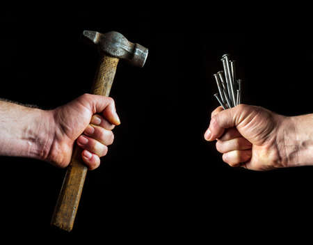 Workers hands hold nails and hammer. Idea or concept of renovation and constructionの写真素材