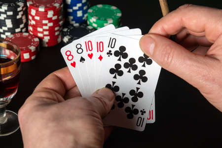 Poker cards with full house or full boat combination. Close up of a gambler hand is holding playing...
