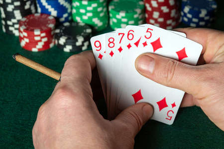 Poker cards with flush combination. Close up of a gambler hand is holding playing cards in poker...
