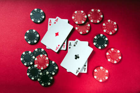 A poker game with a four of a kind or quads hand. Chips and cards on the red table. Successful winの写真素材