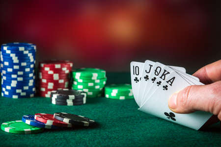Poker cards with royal flush combination. Close up of gambler hand takes playing cards in poker club