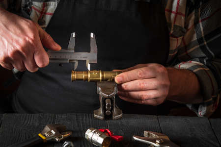The wizard measures the size of fitting using a caliper before connecting water or gas pipe....