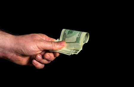Hand holds dollars on black isolated background. Idea of success and wealth. Business and financeの写真素材