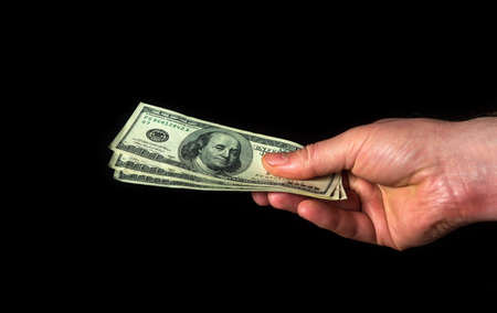 Hand holds dollars on black isolated background. Idea of success and wealth. Business and finance