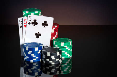 Poker cards with three kind or set combination. Close-up of playing cards and chips in poker club....