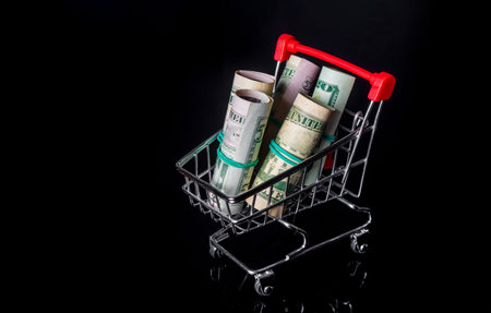 Money or dollars rolled into a tube in a cart on a black background. Sales and shopping concept. Free advertising spaceの写真素材