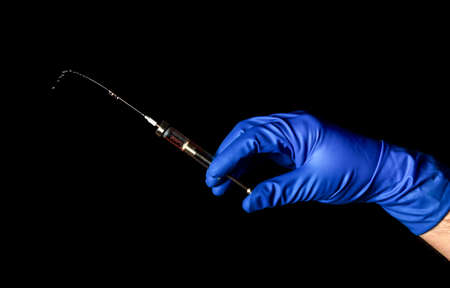 Medical syringe in doctor hand on black isolated background. Health care and medicine idea on black background.の写真素材