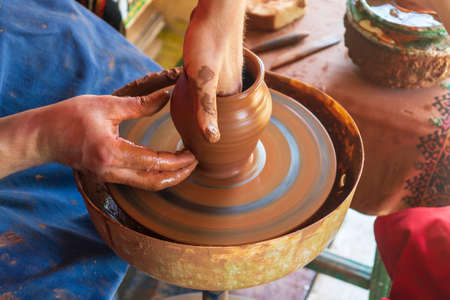 Potter makes on the pottery wheel clay pot. Hands of the master close-up during work. Ancient...
