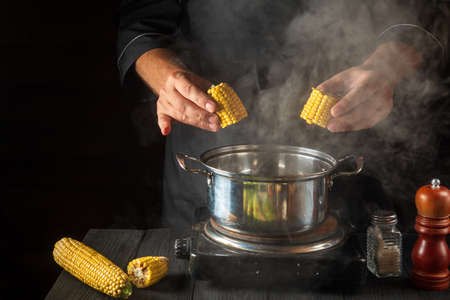A professional chef cooks corn. Close-up of a cook is a hand while cooking in a restaurant kitchen....
