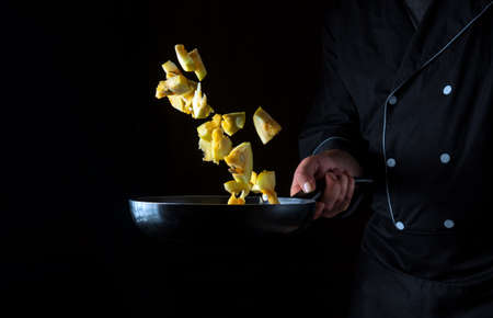 A professional chef prepares zucchini in a pan. Cooking vegetables healthy vegetarian food and meal on a dark background. Free ad spaceの写真素材