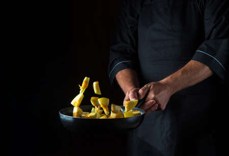 Chef prepares zucchini in a pan. Cooking vegetables healthy vegetarian food and meal on a dark background. Free advertising space.の写真素材