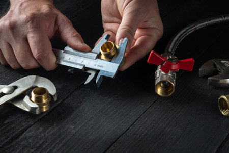 Wizard measures the size of fitting using a caliper before connecting water or gas pipe. Close-up of...
