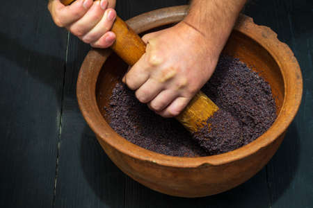 Grinding poppy seeds in an old clay pot for making kutya or pies. The national dish is prepared before any holidayの写真素材