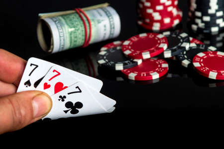 Poker cards with three of a kind or set combination. Close up of gambler hand takes playing cards in...