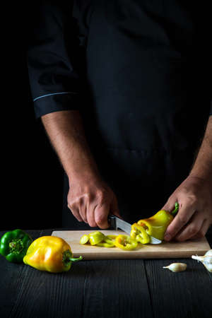 The chef is cutting bell peppers for salad in the restaurant kitchen. Close-up of a cook hands while working.の写真素材