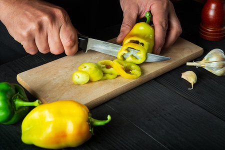 Chef is cutting bell peppers for salad in the restaurant kitchen. Close-up of a cook hands while...