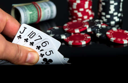 Poker cards with flush combination. Close up of gambler hand takes playing cards in casino