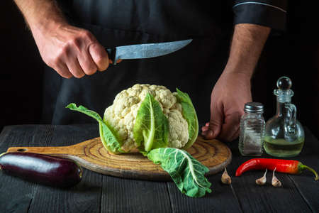 Cook is cutting cauliflower in a restaurant kitchen. The idea of a delicious diet for breakfast or dinner.の写真素材