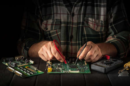 Computer or electronics repair. Master tester checks the electronic board in the workshopの写真素材