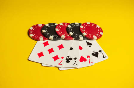 Poker game with four of a kind or quads combination. Chips and cards on yellow table. Successful and...