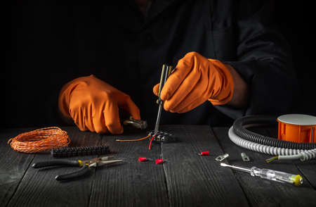 Electrical connection in the workshop of a master electrician. Close-up of hands of a master...