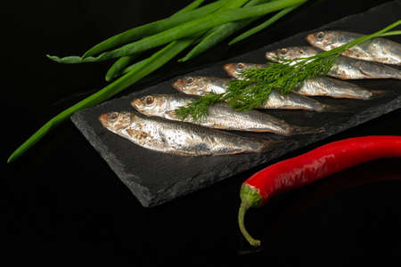 Sprat with vegetables on a serving board. Small salted fish with onion and pepper.の写真素材