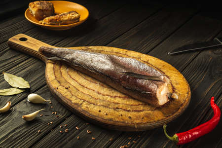 Freshly frozen Merluccius fish on a kitchen cutting board before preparing a diet menu. Mediterranean cuisine. Delicious fish recipe.の写真素材