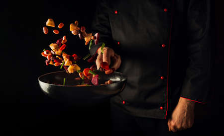 Cooking vegetables by chef hands on dark background copy space. food concept. Vegetable menu for the hotelの写真素材