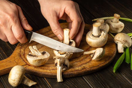 Cooking Agaricus mushrooms by the hands of the cook in the kitchen. Peasant foods.