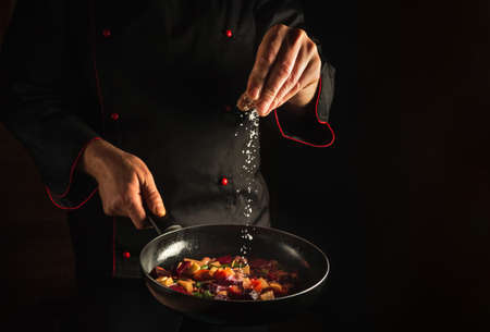 Professional chef adds salt to a steaming hot pan. Menu idea for a hotel with advertising space. asian foodの素材 [FY310185775666]