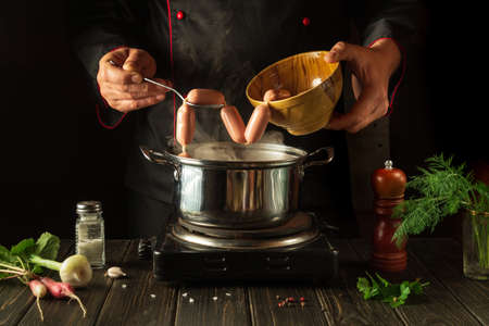 For dinner need to cook delicious meat sausages in a saucepan. Chef in the kitchen at work. Menu...
