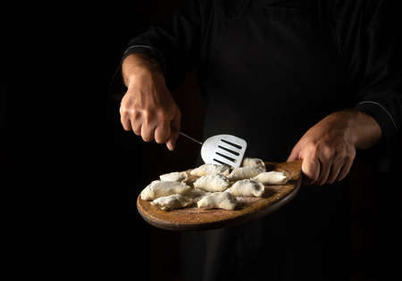 Cooking dumplings or dumplings by chef hands in the kitchen. Delicious lunch or breakfast concept on black background.の写真素材