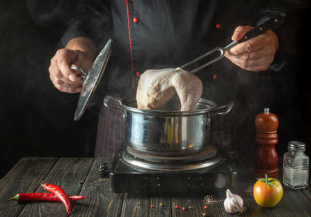 Cooking delicious broth from chicken legs and vegetables by the hands of a chef in the kitchen of a restaurant or hotel.の写真素材