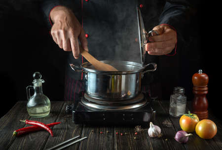 In the kitchen, dietary soup is prepared by the chef hands in a hot pot. Delicious food for lunch in a restaurant.の写真素材