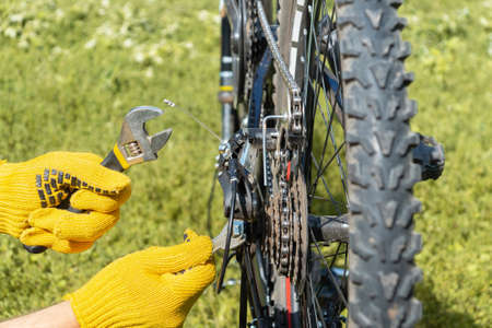 Cropped shot of a male mechanic repairing a bicycle, hands of a master in gloves repairing a bicycle...