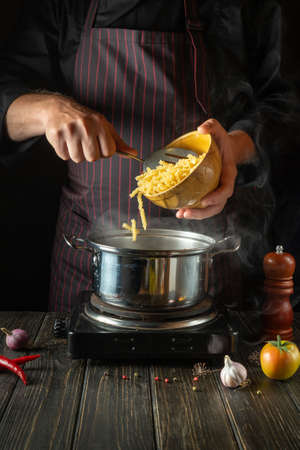 A professional chef prepares organic pasta in a pot in the kitchen. Healthy food recipe or Italian dishの写真素材