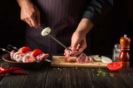 The process of cooking shish kebab from raw lamb meat in the kitchen with the hands of a chef. Asian Traditional Cuisineの写真素材
