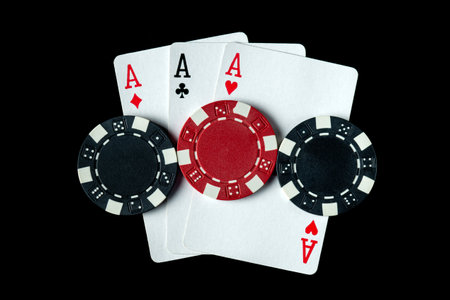 Poker game with three of a kind or set cards combination. Chips and cards on a black table in a...