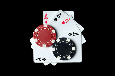 Playing cards with a winning combination of four of a kind or quads and chips on a black table in a...