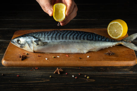 The chef adds fresh lemon juice to raw mackerel fish before cooking with ingredients and aromatic spices.の写真素材