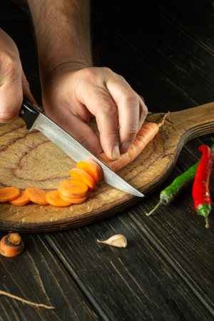 The chef cuts carrot on a cutting board for cooking ajika. Peasant delicious food.の写真素材