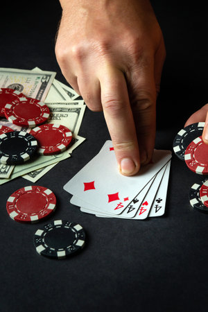 Player points with his finger at a winning four of a kind or quads combination in poker game on a...