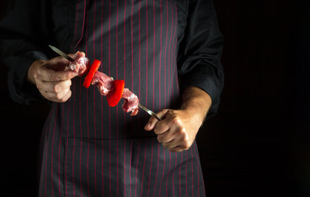 The cook holds in his hands a barbecue with raw veal meat and vegetables on a skewer. asian foodの写真素材
