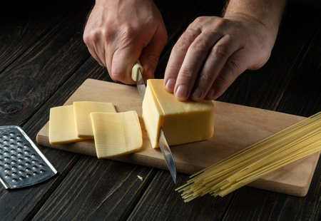 The cook cuts milk cheese on the cutting board of the restaurant kitchen for preparing snack...