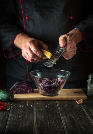 The cook adds cheese to a fresh red cabbage salad in a restaurant kitchen. Cooking healthy or vegetarian foodの写真素材