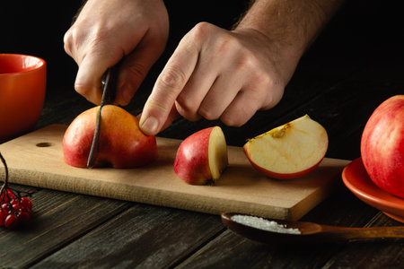 The chef cuts apples on a cutting board to make compote or fruit juice. Apple diet for a set of vitamins. Work environment on the kitchen tableの写真素材