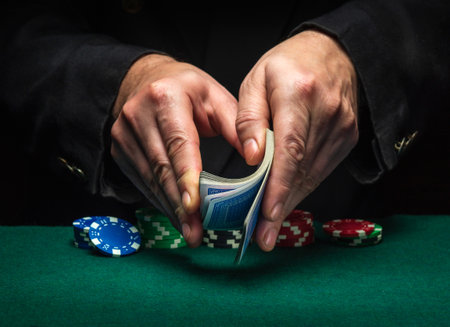 Shuffling of playing cards with the hands of a dealer or a croupier in a poker club on a green table with playing chips. Poker game or gaming business conceptの写真素材