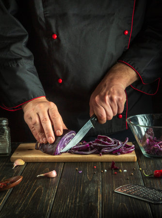 Professional chef cuts red cabbage with a knife. Cooking vegetable salad in the restaurant kitchen. The idea of a vegetable dietの写真素材