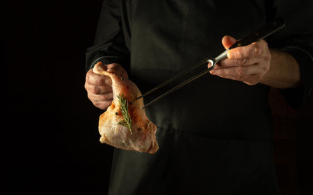 The chef prepares a chicken leg in the restaurant kitchen. Preparing raw meat for grilling in the cook's hand. copy spaceの写真素材